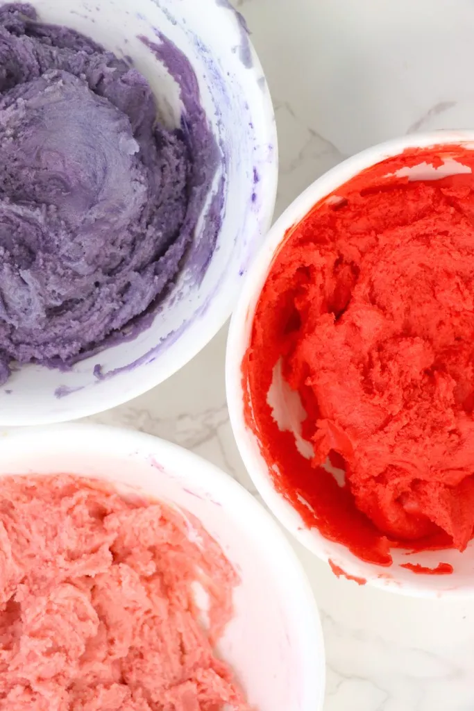 Three bowls with pink, red, and purple divided Valentine's whoopie pie dough.