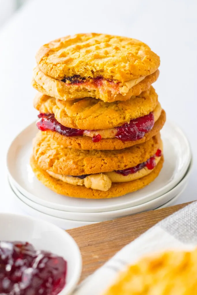 Peanut butter and Jelly Cookie Sandwiches stacked on a white plate.