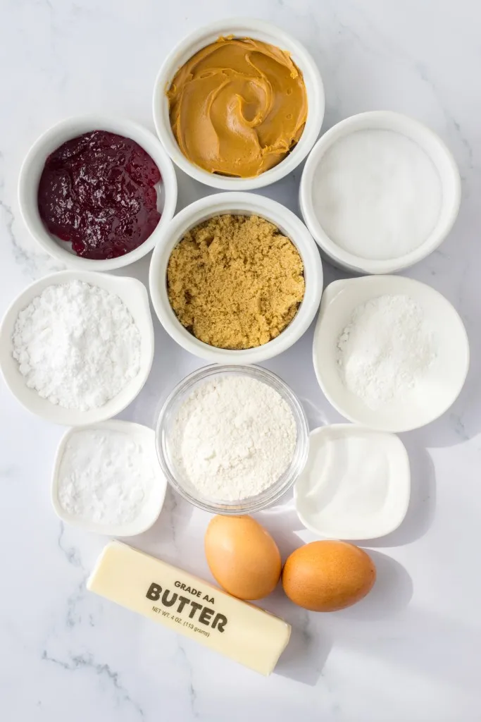 Peanut butter and jelly cookie sandwich ingredients on a white countertop.