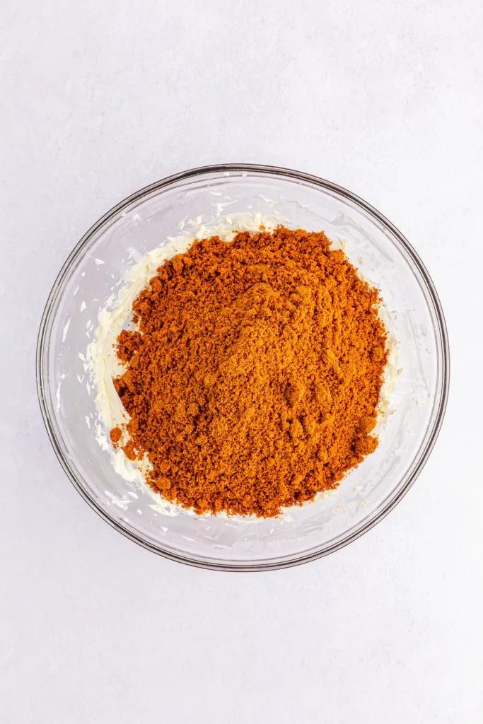 Large mixing bowl with beaten cream cheese and Biscoff cookie crumbs.