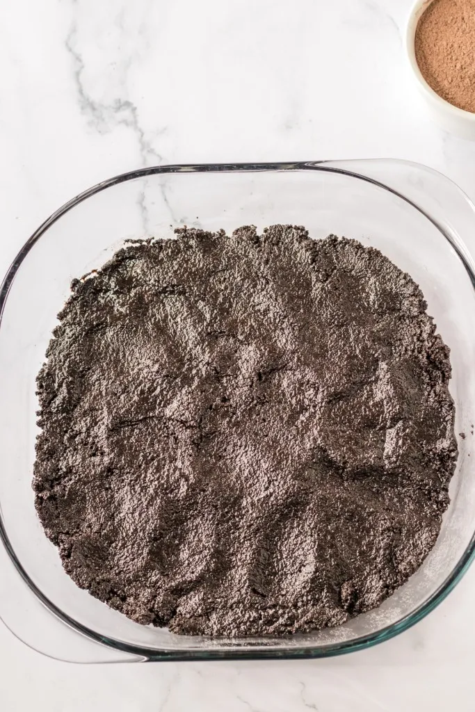 9x9 baking dish with crushed chocolate sandwich cookies and melted butter mixture pressure down into the dish.