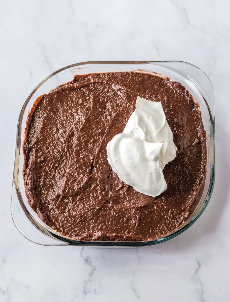 Baking dish with chocolate instant pudding mixture spread over the peanut butter layer but the remaining whipped cream being added on top.