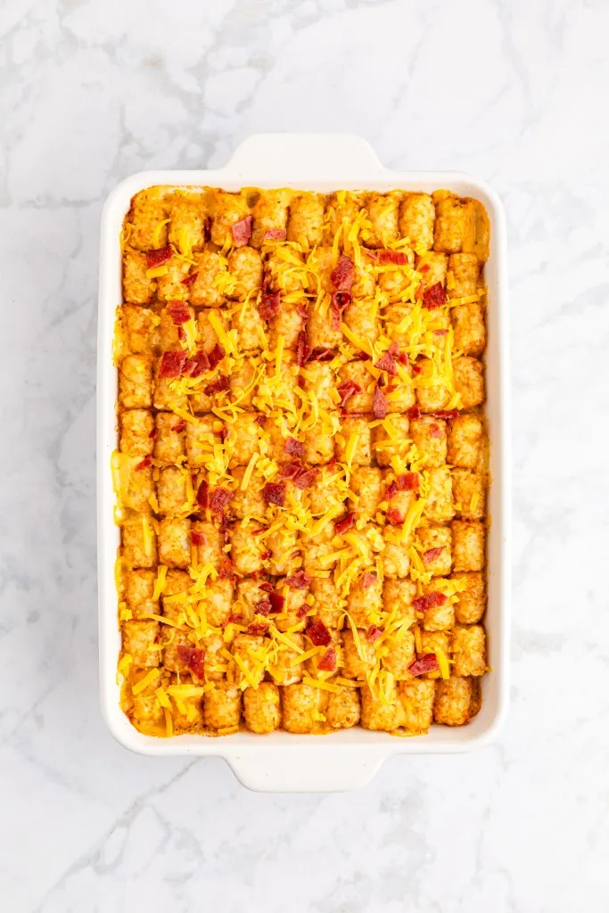 Baked chicken tater tot casserole, topped with shredded cheese and crumbled bacon.