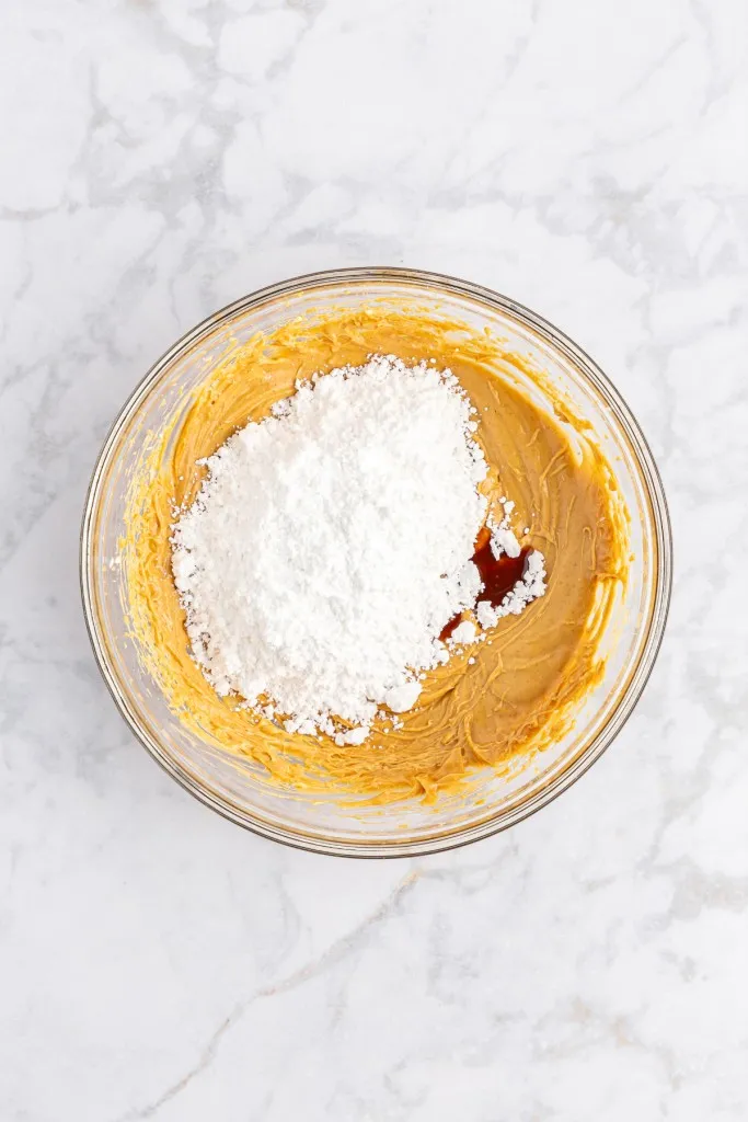 Large mixing bowl with creamy peanut butter, unsalted butter, powdered sugar, and vanilla extract.