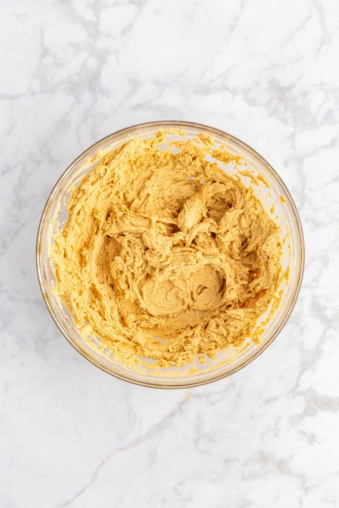 Overhead view of peanut butter mixture in a large mixing bowl for chocolate covered peanut butter balls.