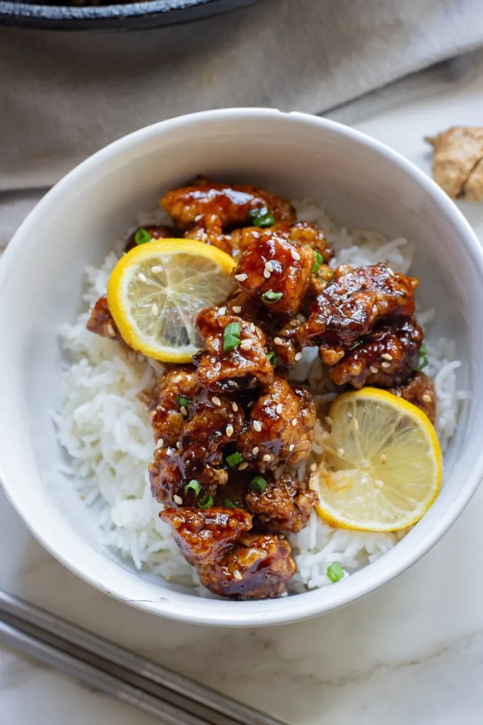 Overhead view of a bowl of Chinese lemon chicken with white rice.