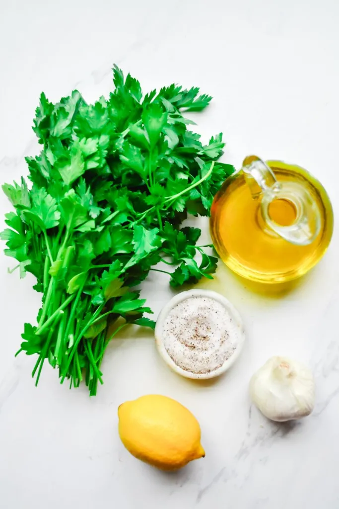 Ingredients for homemade gremolata on a white marble countertop. 