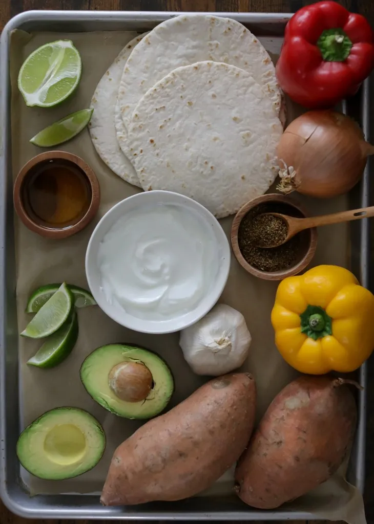 Ingredients for sweet potato fajitas on a baking sheet.