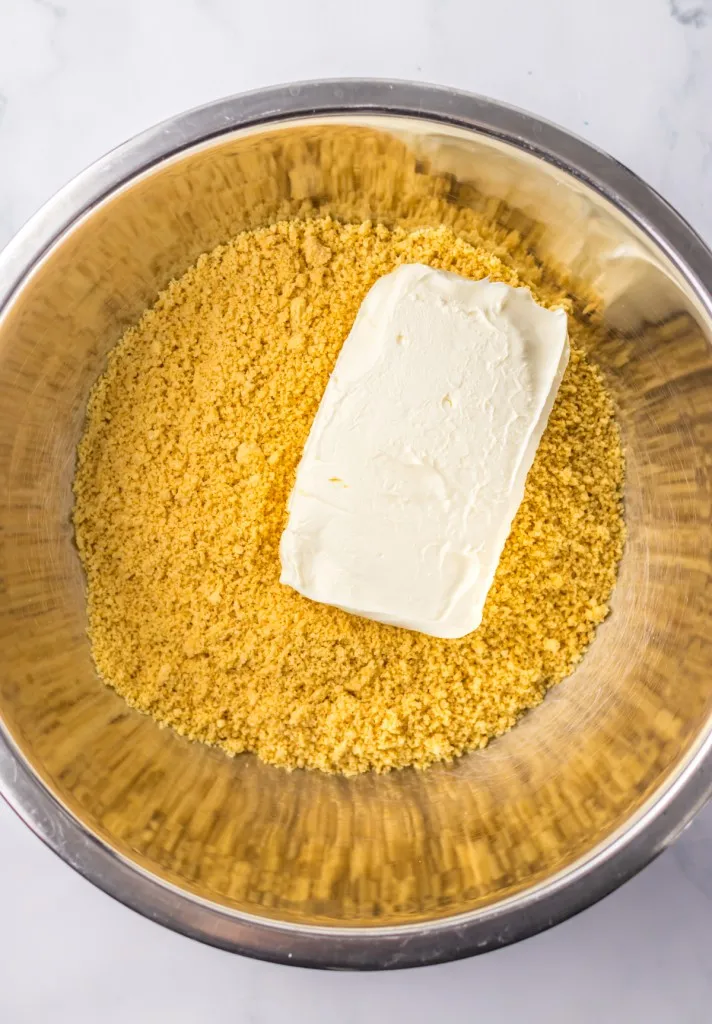 Medium mixing bowl with processed vanilla Oreos and softened cream cheese.