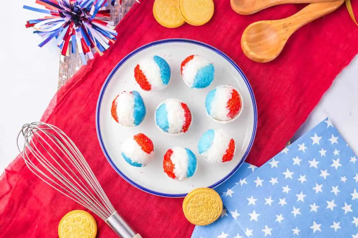 Overhead view of snow cone Oreo truffles with themed table decorations, metal whisk, and Golden Oreos.