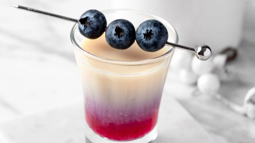 A layered shot with fresh blueberries over the top.