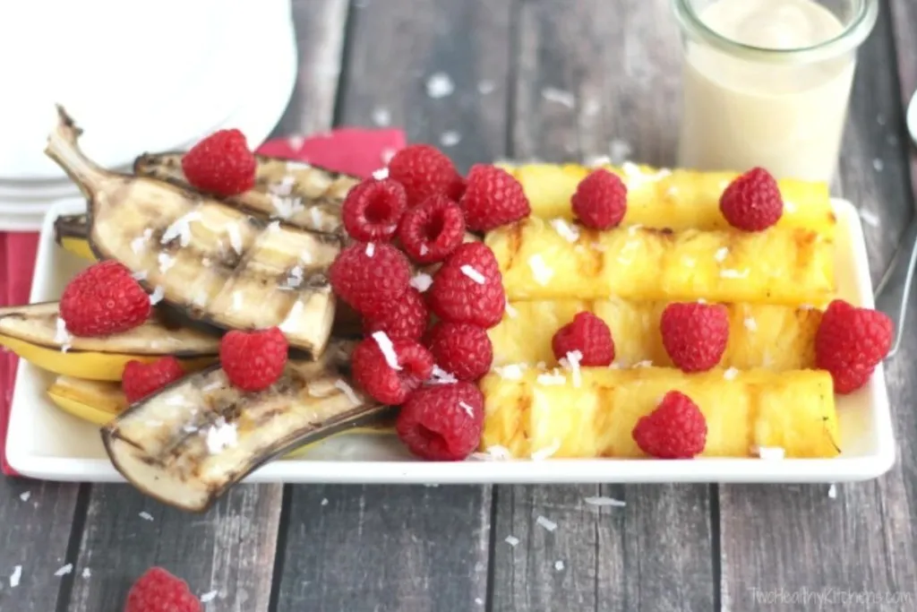 A plate of grilled bananas in peel, berries and pineapple.