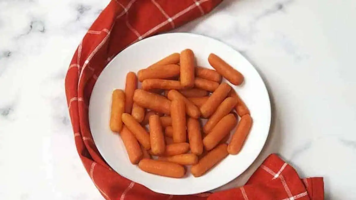 A plate of cooked baby carrots.