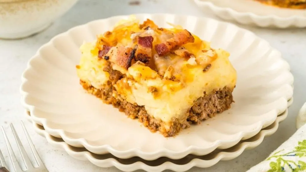 a serving of meatloaf and potato casserole with bacon over the top.