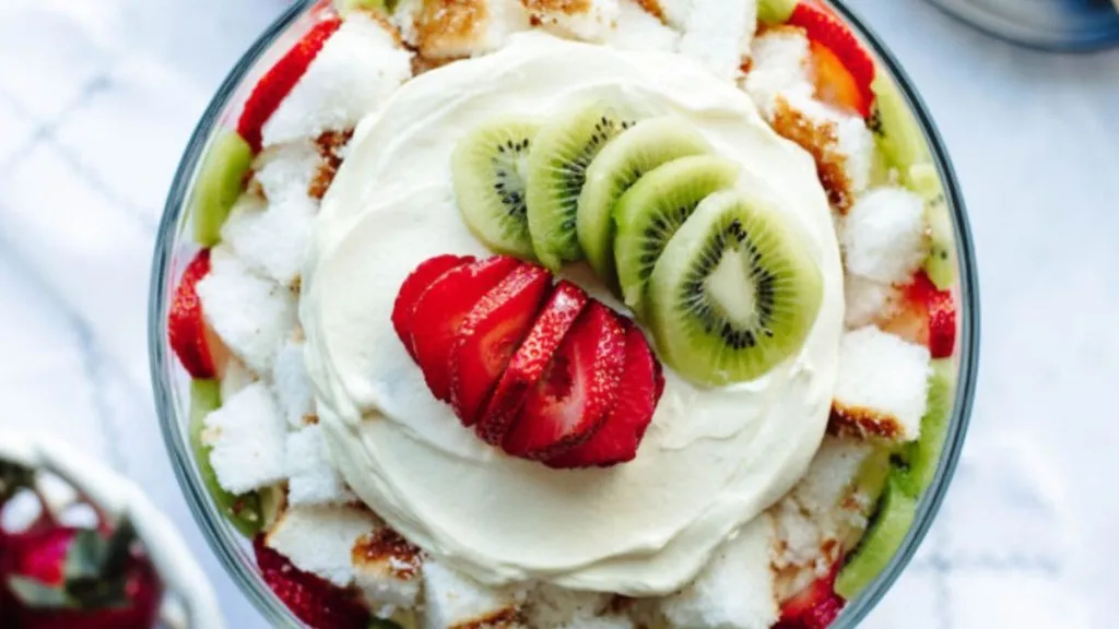 A trifle of cake, strawberries, cream and kiwi slices.