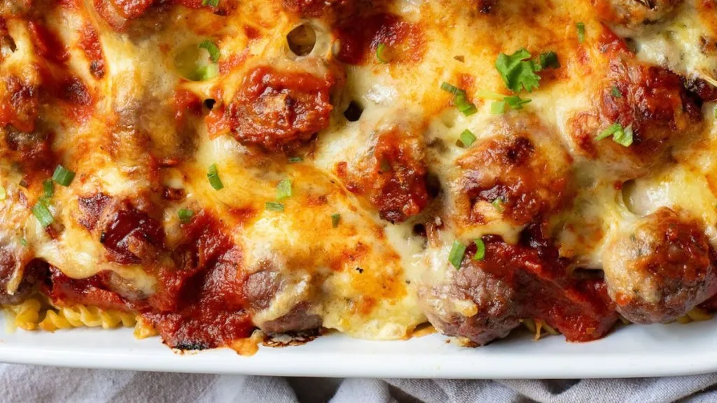 a casserole dish of meatballs, swimming in sauce with cheese over top.