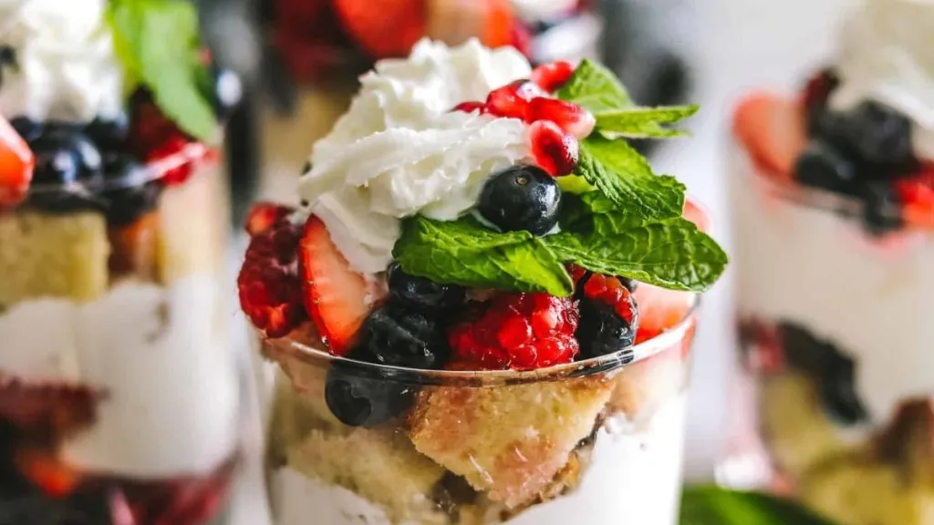 Trifle glasses with butter cake, whipped cream and mixed summer berries.