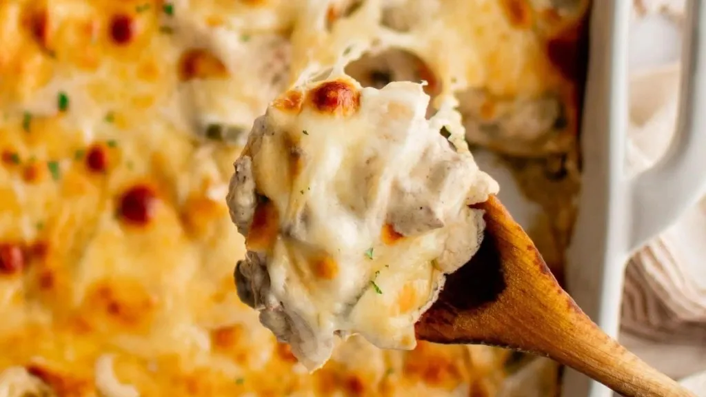 a serving spoon with ultra cheesy cheese steak casserole.