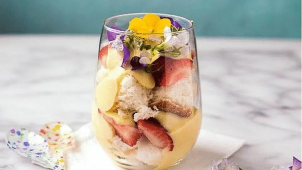 A stemless wine glass of cake, custard and berries.