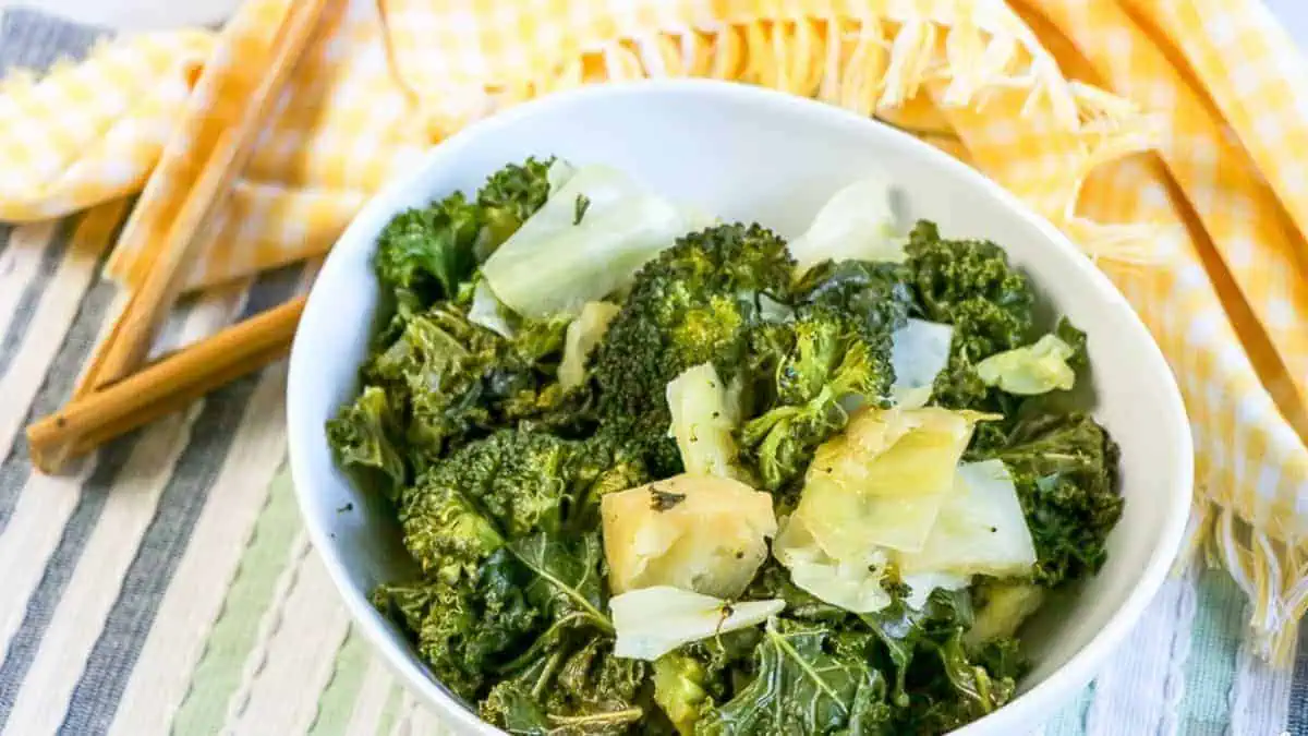 a bowl of spinach and broccoli with cheese over top.