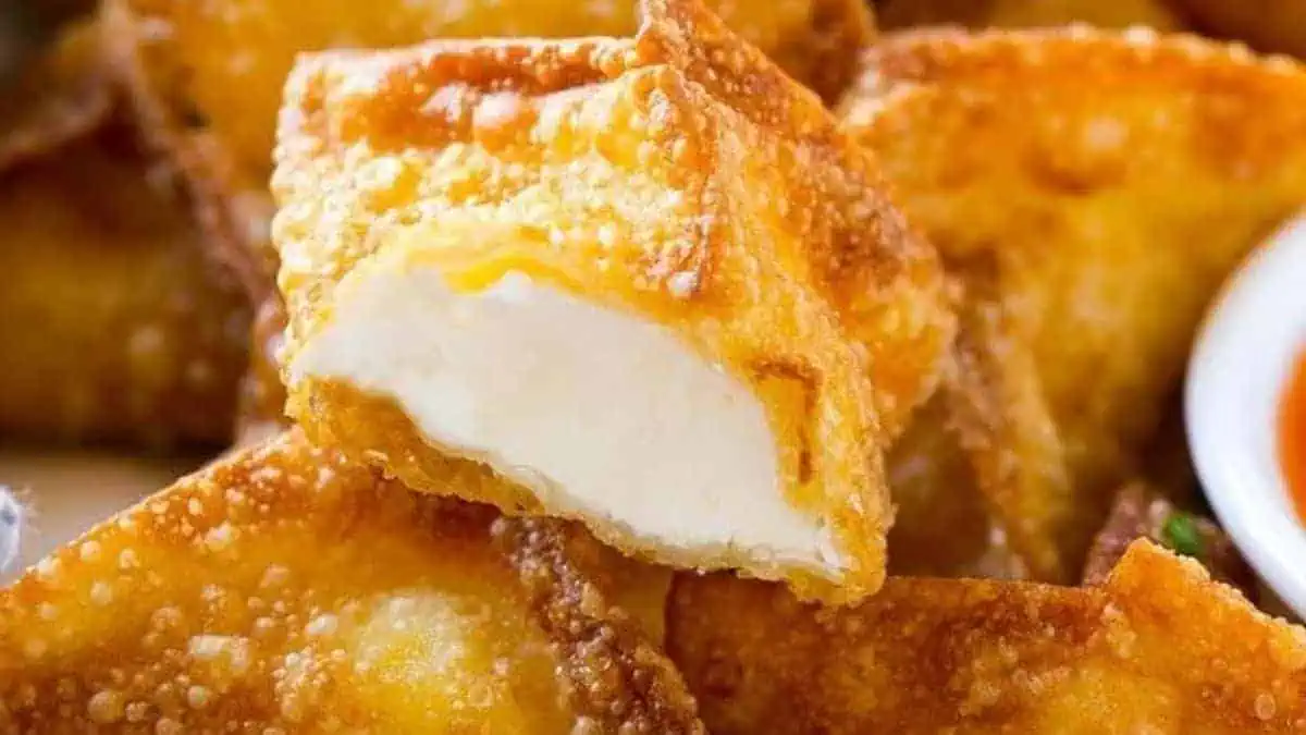 a plate of cream cheese wontons, fried to perfection with dipping sauce