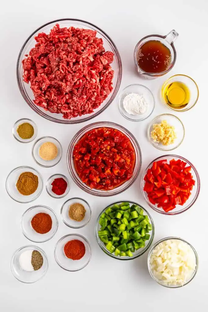 Ingredients for Carne Picada in separate bowls on a white countertop.