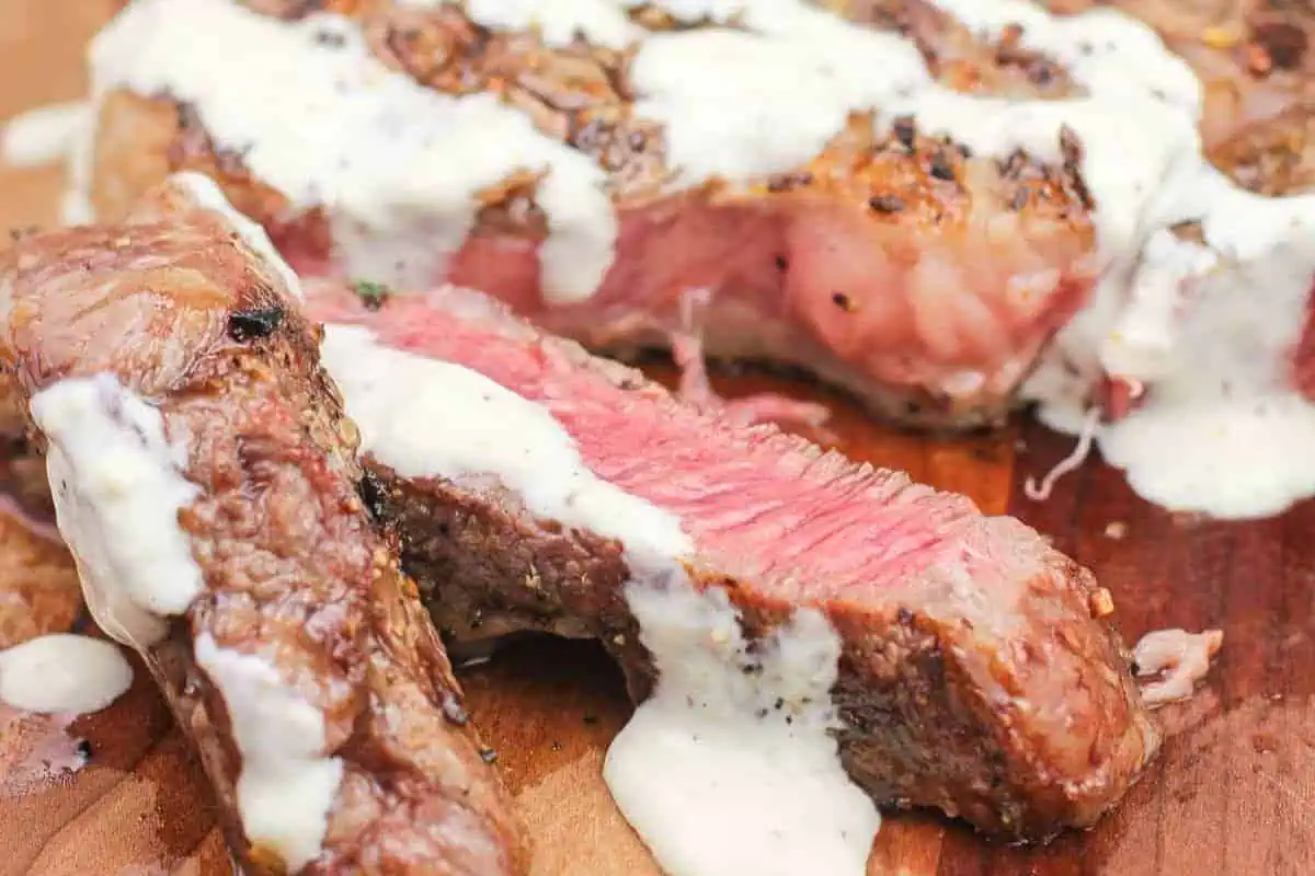 A cut steak with white sauce.