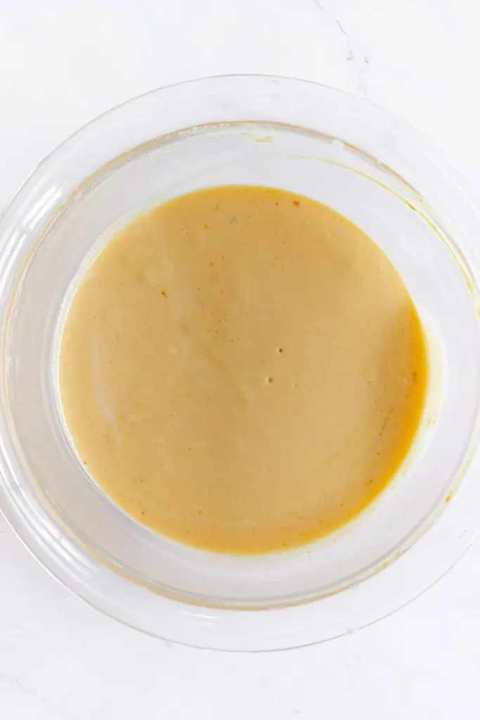 Glass mixing bowl with melted butter, chocolate chips, sugar, and eggs.