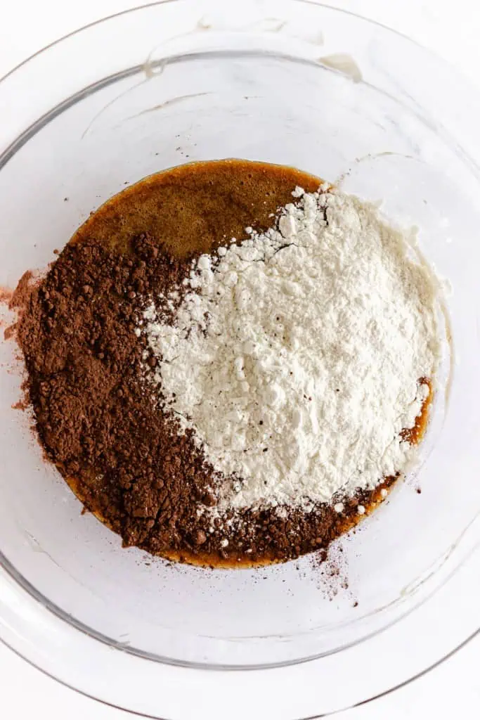 Glass mixing bowl with melted butter mixture, salt, cocoa powder, and flour.