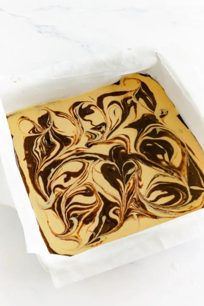 Cream cheese mixture poured over brownie batter and swirls made with a skewer or butter knife.