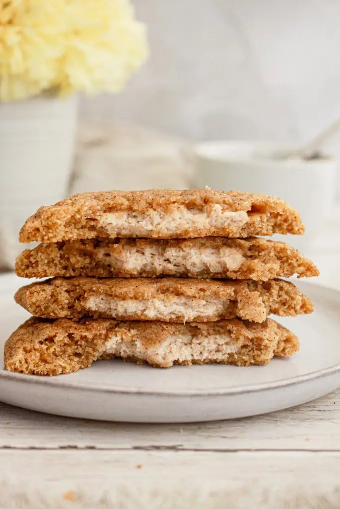 Stacked and broken in half pumpkin cheesecake cookies on a cream plate.