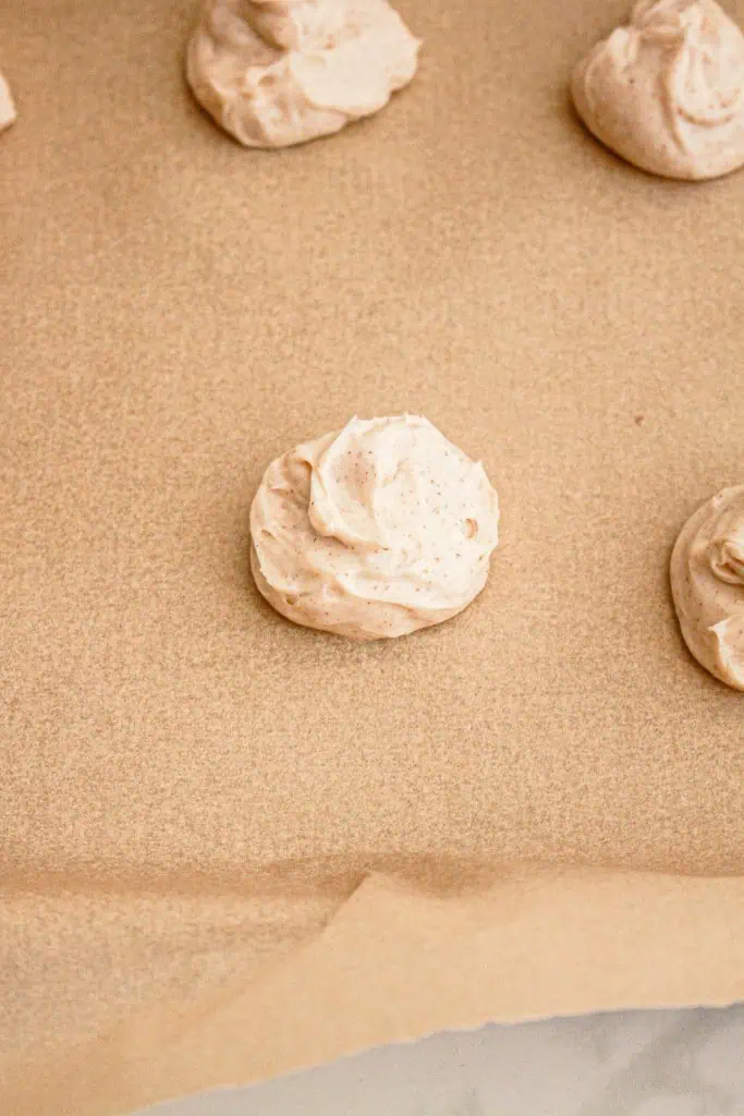 Scoops of pumpkin cheesecake cookie filling placed on a parchment paper-lined baking tray.