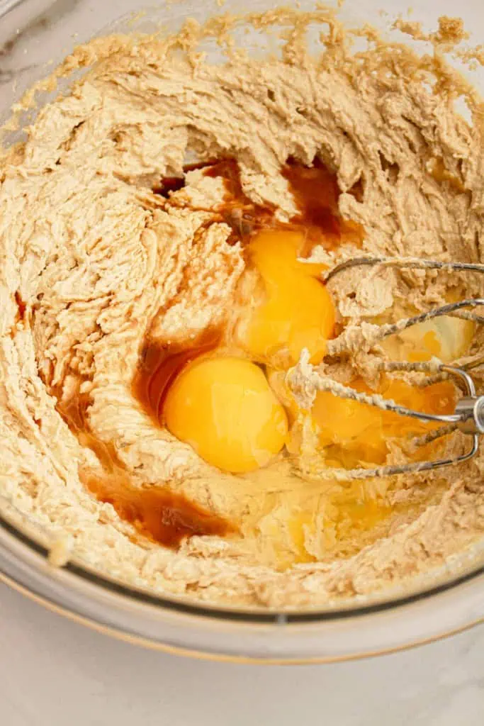 Pumpkin cheesecake cookie dough ingredients beaten together with an electric beater in a large bowl. 