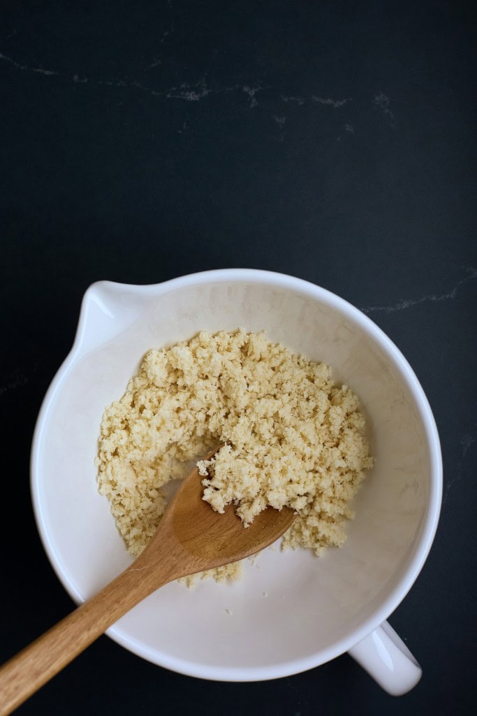 Large mixing bowl with Panko bread crumbs soaked in cream, wooden spoon in the bowl.