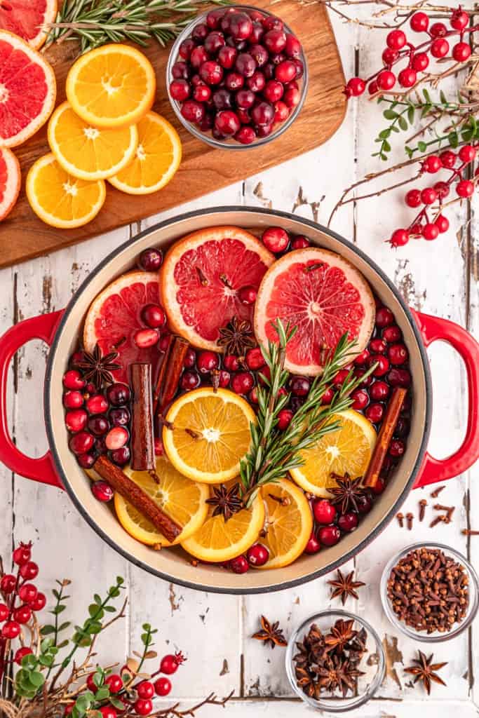 Overhead view of Christmas simmering pot, ingredients on a wooden kitchen board.