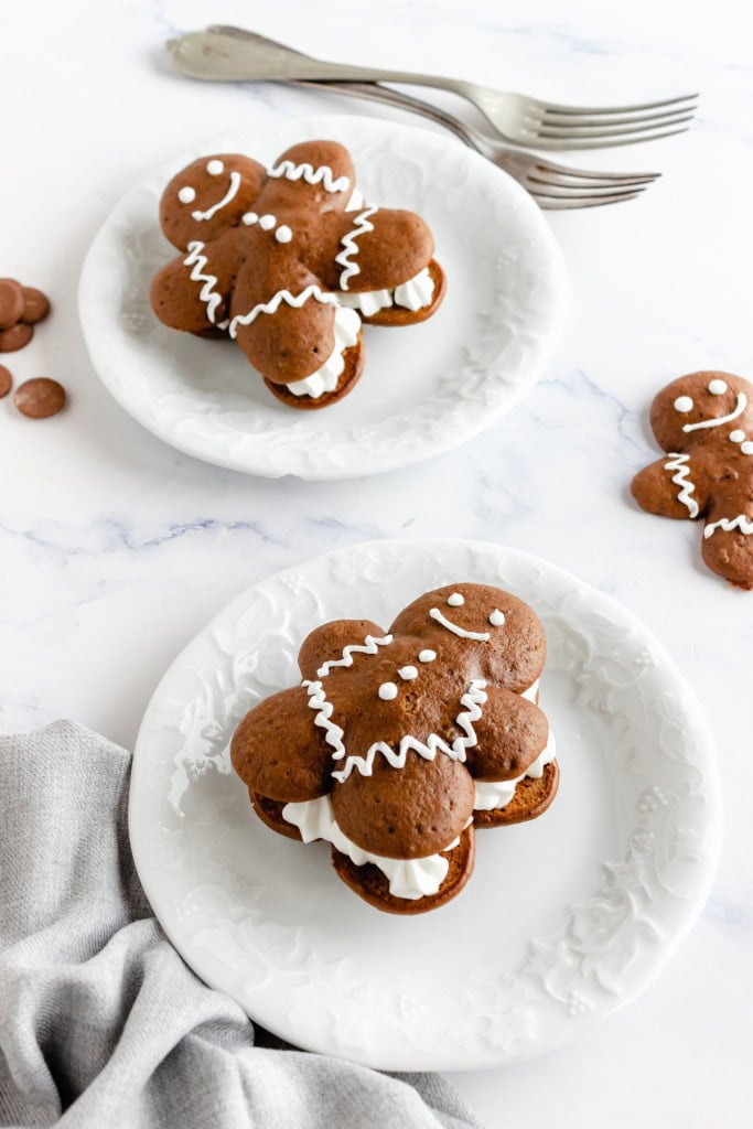 Gingerbread chocolate whoopie pies served in white dessert bowls, two silver forks on a marble countertop. 