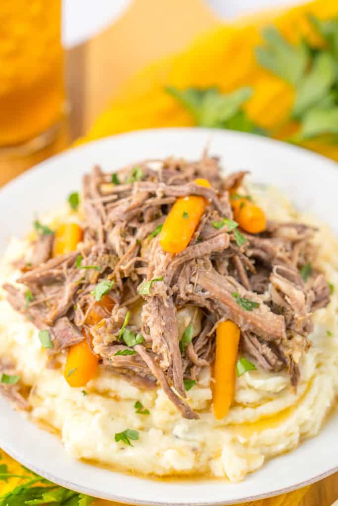 Close up of slow cooker garlic herb pot roast served over mashed potato.
