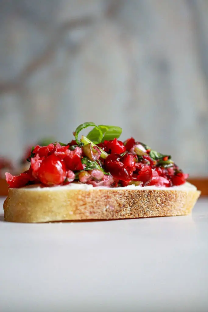 Side view of bruschetta with cream cheese spread and topped with cranberry jalapeno salsa.