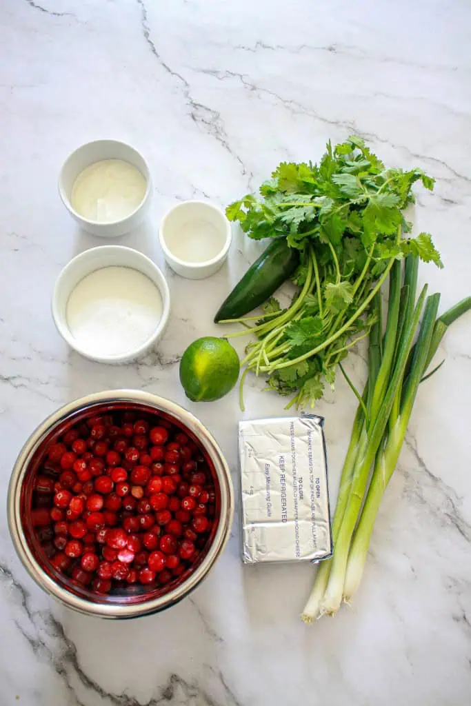 Ingredients to make cranberry jalapeno salsa on a marble countertop.