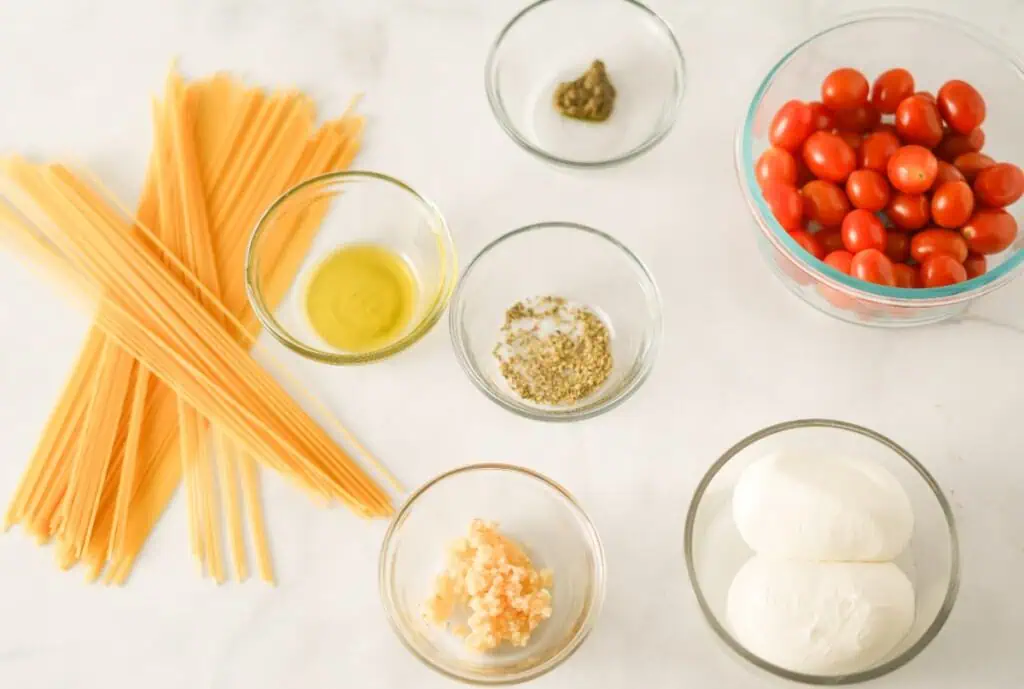 Ingredients to make creamy burrata pasta on a white marble countertop.