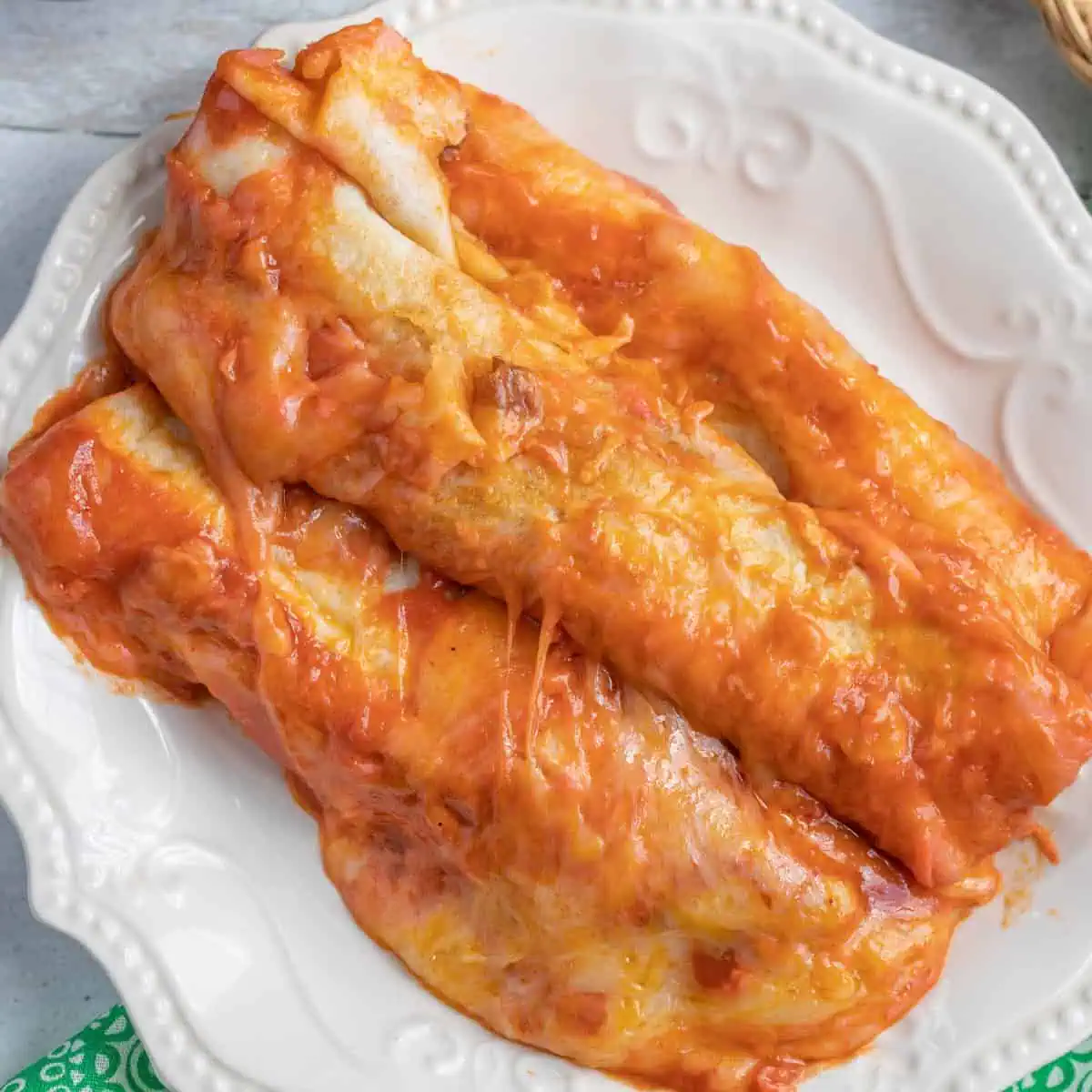 OVERHEAD shot of cheesy beef enchiladas on a white plate