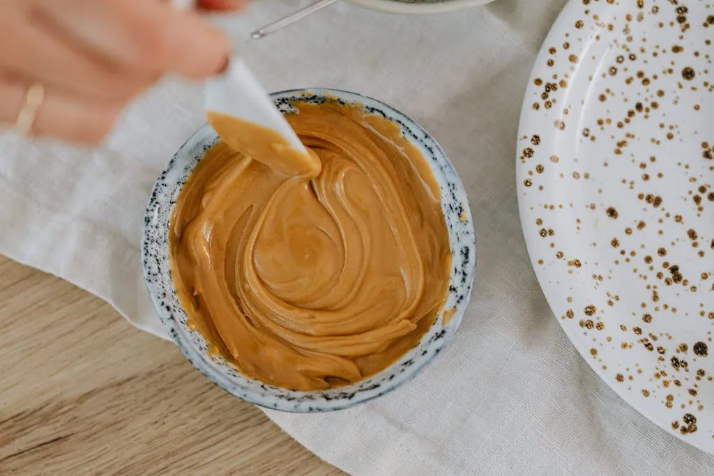 A creamy swirl of peanut butter captured in a ceramic bowl from above.