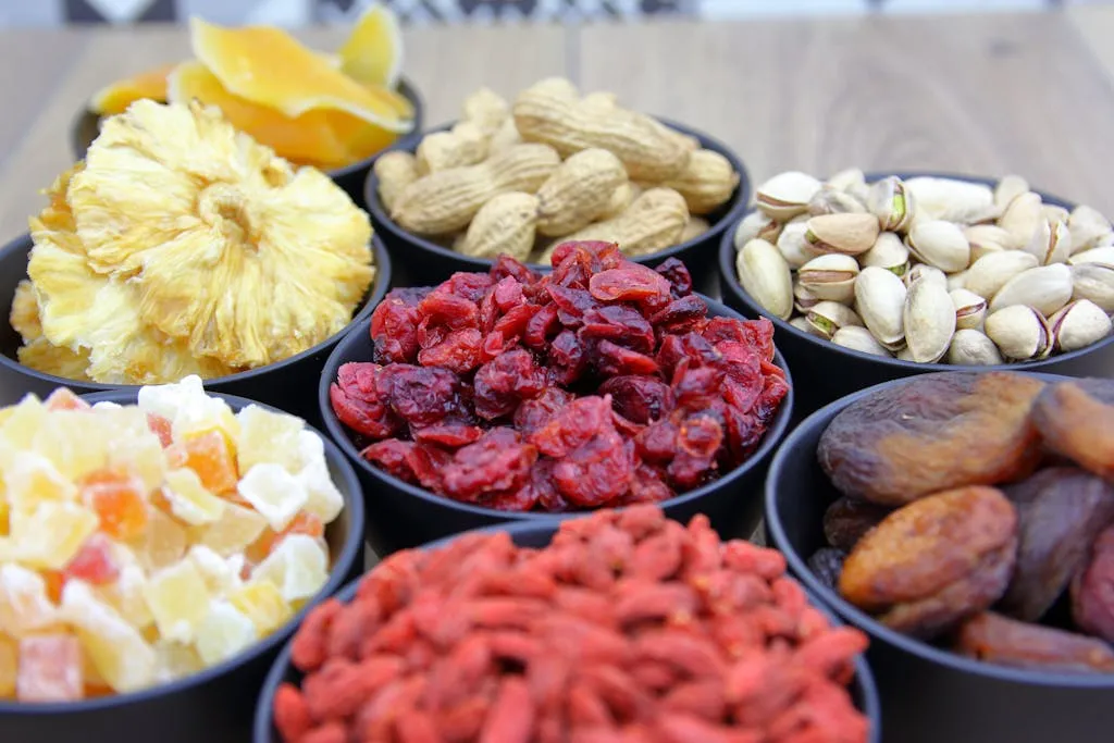 A vibrant assortment of dried fruits and nuts displayed in black bowls on a wooden table.