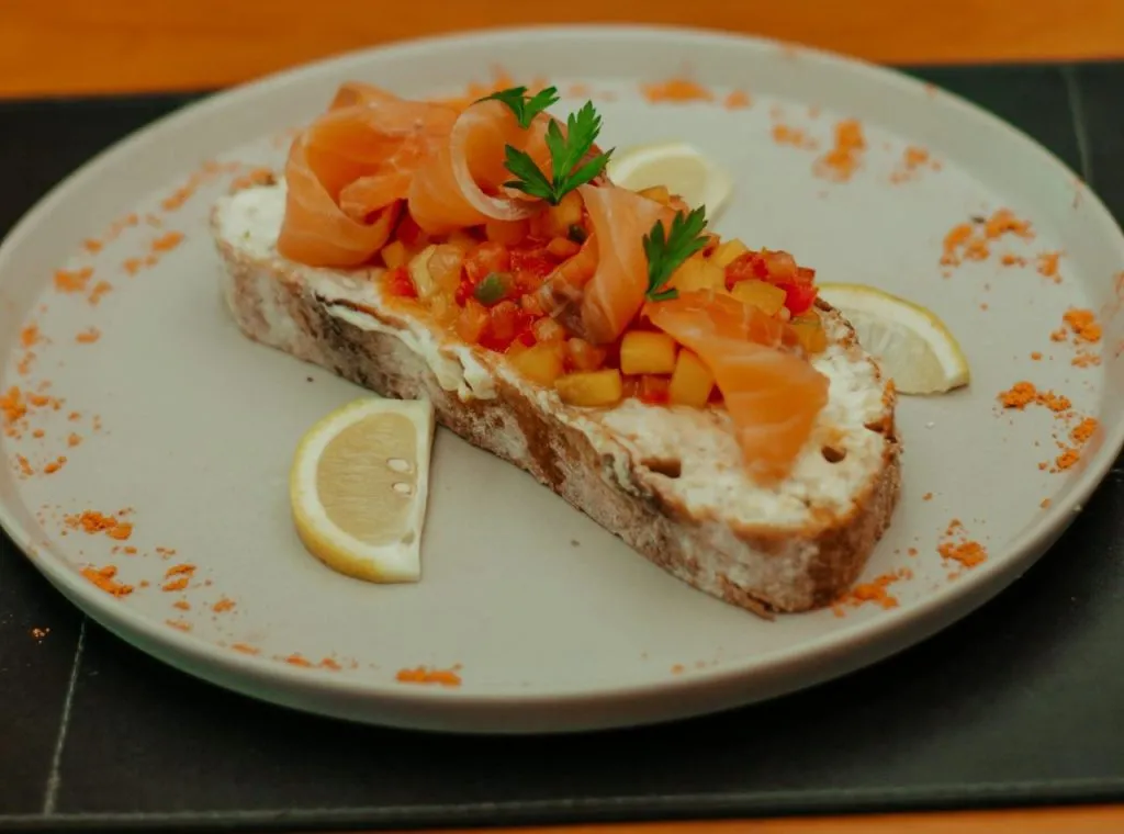 Delicious open-faced sandwich with smoked salmon, lemon slices, and garnish on a rustic bread.