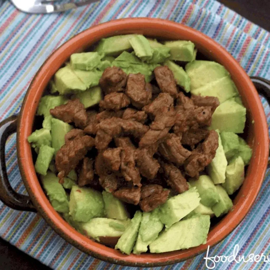 a bowl of perfectly seasoned chili lime steak bites with fresh diced avocado