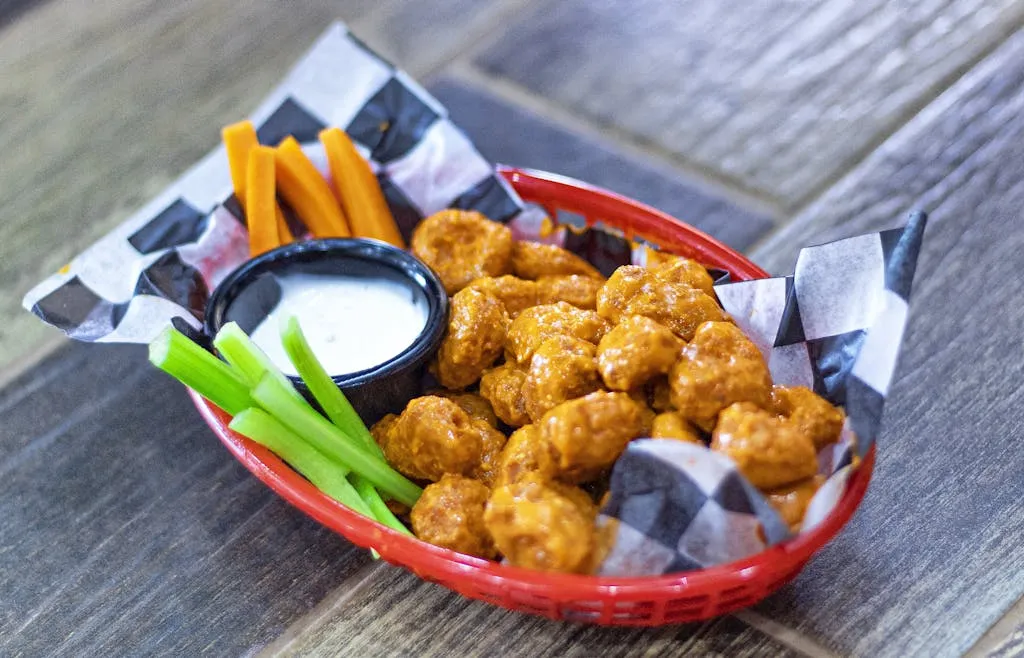 Crispy buffalo cauliflower paired with carrots, celery, and ranch dip in a vibrant basket.