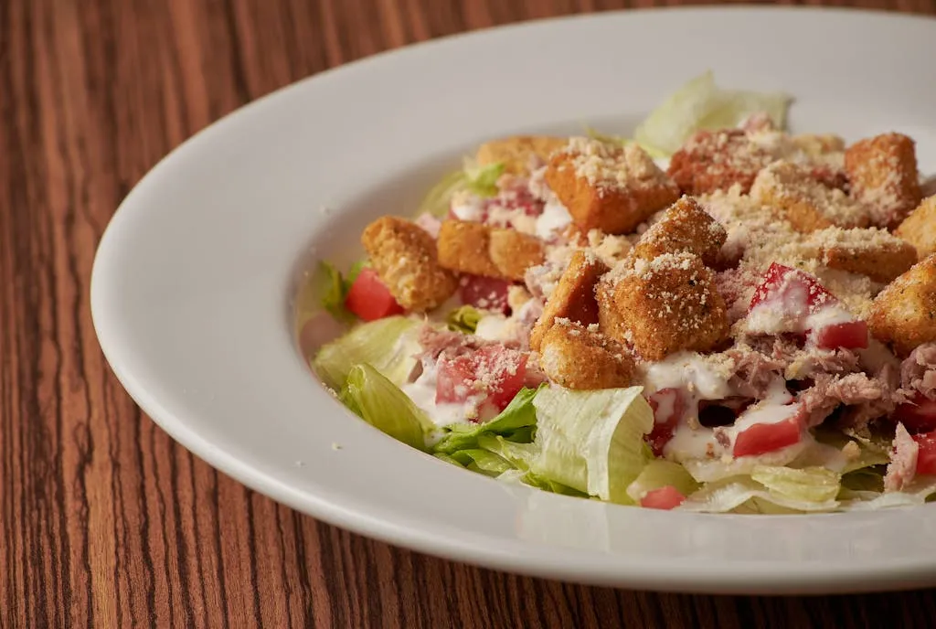 Delicious Caesar salad served with croutons, parmesan, and fresh vegetables on a wooden table.