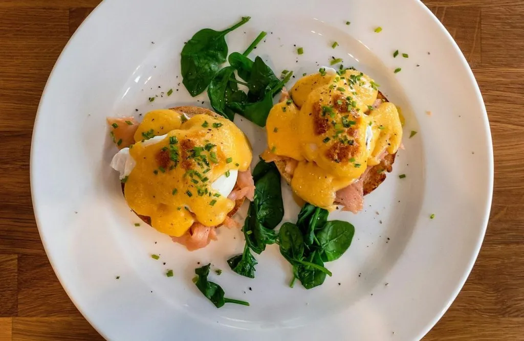 Delicious Eggs Benedict with spinach on a white plate perfect for breakfast or brunch.