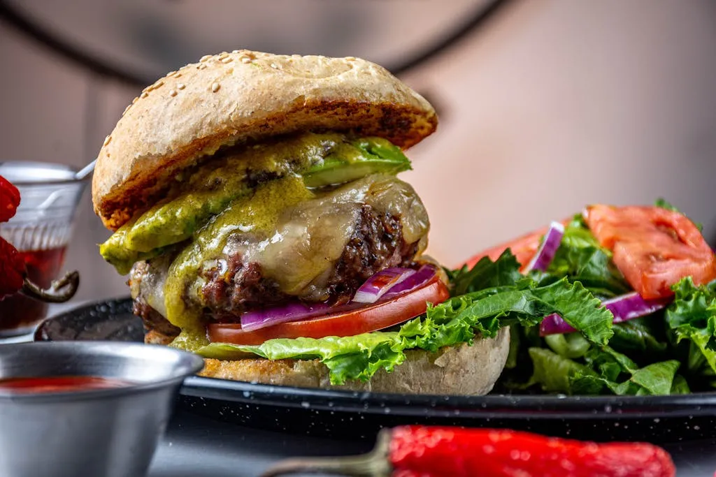 Delicious gourmet beef burger with lettuce, tomatoes, and cheese served on a plate.