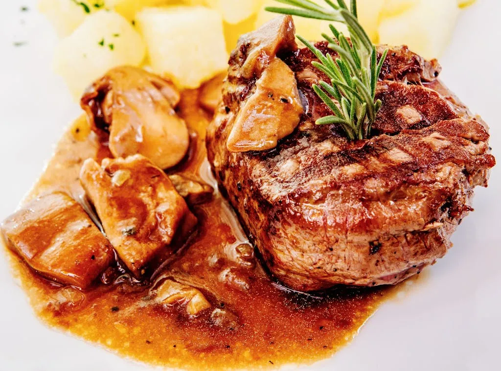 Savory steak with mushroom sauce and potatoes, garnished with rosemary.